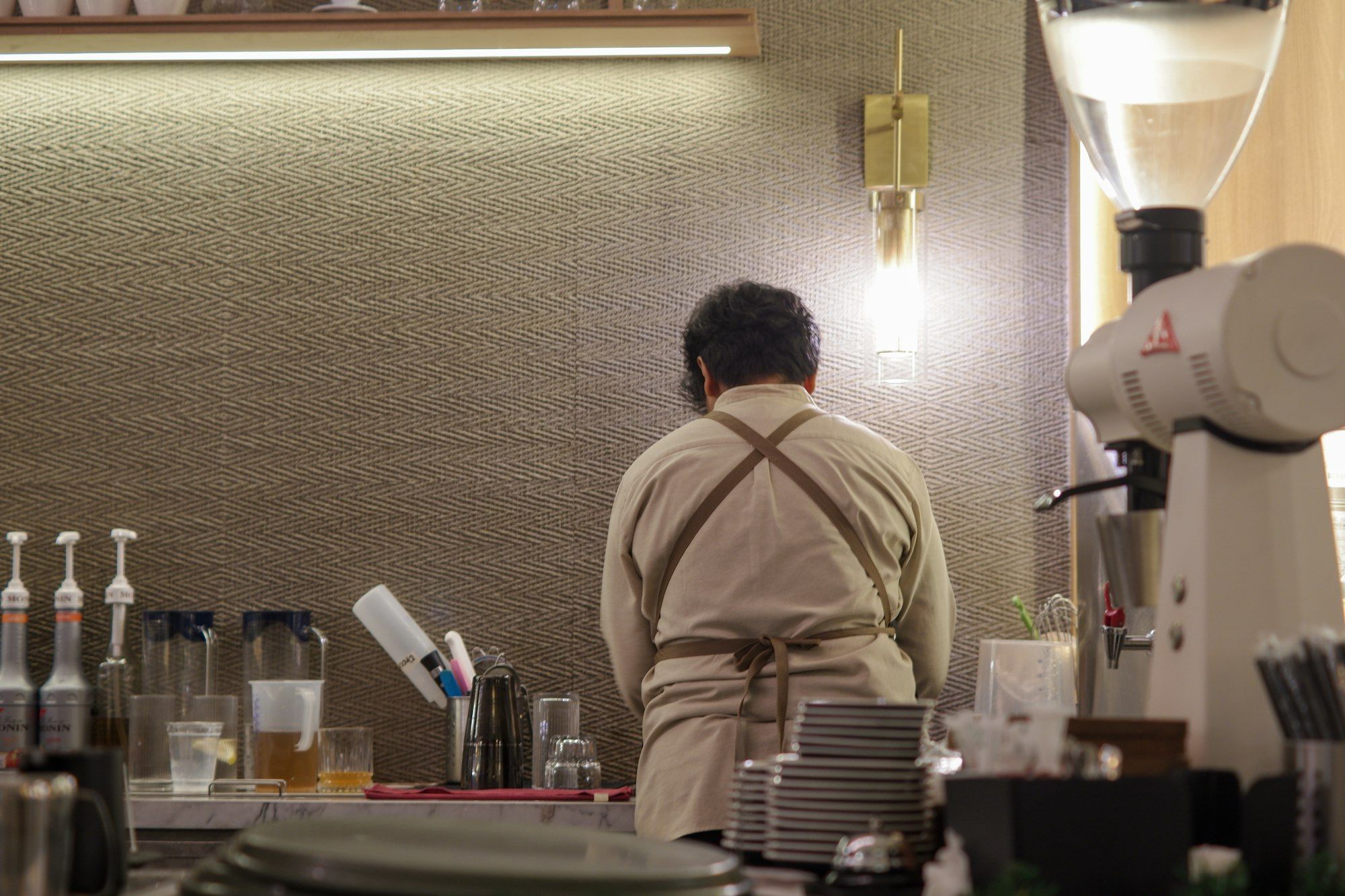 A barista preparing drinks behind the counter of a busy cafe